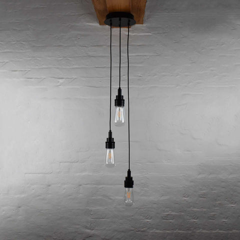 Bo Bathroom Cluster pendant light with three hanging bulbs and black fixtures against a gray brick wall