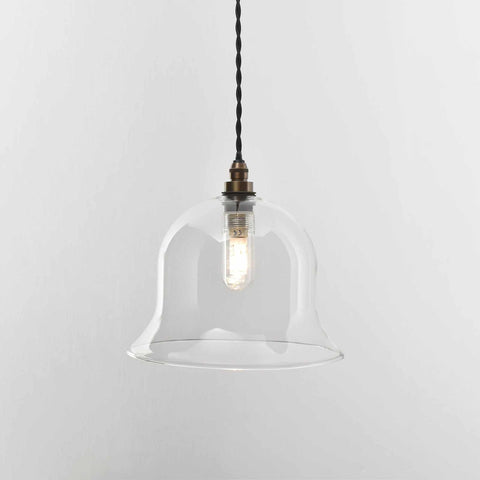 Bathroom pendant light with clear glass shade and vintage-style bulb suspended by twisted black cord