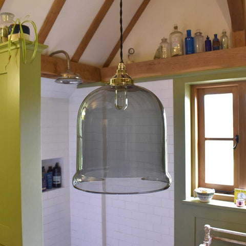 Hythe medium smoked glass shade pendant light with brass fixture in rustic bathroom interior
