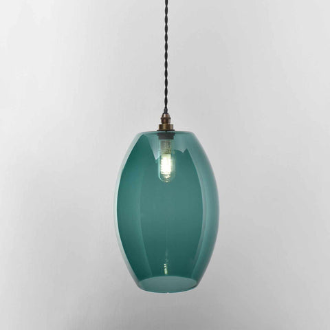 Large teal glass shade pendant light with adjustable cord hanging against a plain background