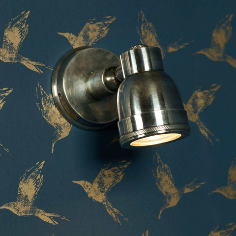 Henton Bathroom Adjustable Spotlight in antique silver with swivel joint, wall-mounted on dark wallpaper with gold bird design