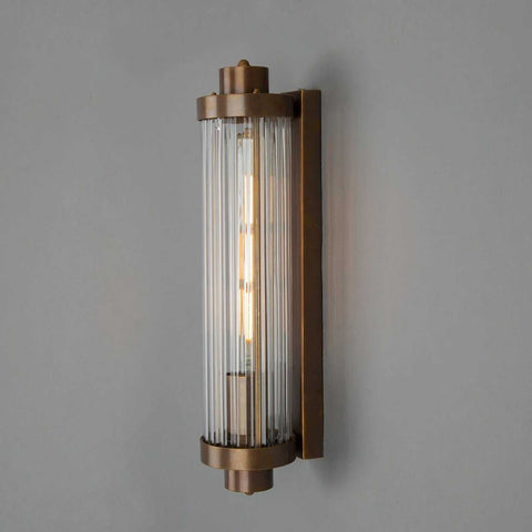 Louise Bathroom Wall Light with art deco reeded glass and bronze finish mounted on gray wall