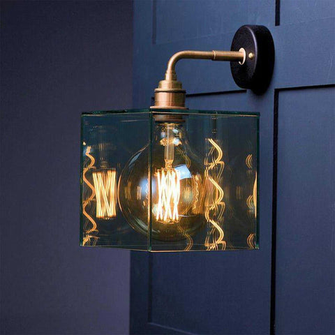Bramley Bathroom Clear Globe Wall Light with LED filament bulb on blue wall.