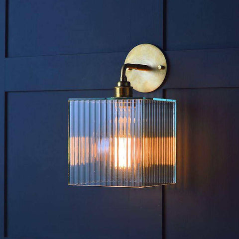 Bramley Bathroom Reeded Globe Wall Light with handcrafted glass shade and brass base, warm LED filament bulb illuminated on dark wall