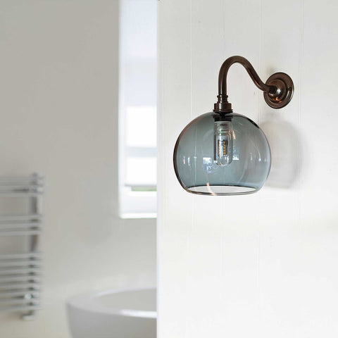 Soho Small smoked glass bathroom wall light with curved bronze mount and exposed bulb in modern bathroom setting