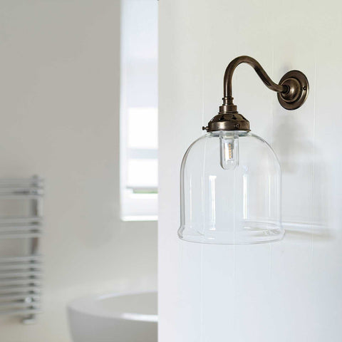 Hythe Small Clear Glass Shade bathroom wall light with bronze finish and clear glass shade mounted on white bathroom wall