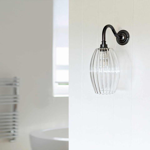Camber small ribbed glass shade bathroom wall light with black metal arm and vintage style, mounted on white wall in bathroom