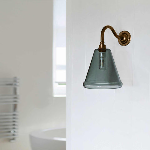 Rye Small Smoked Glass cone shade bathroom wall light with brass arm mounted on white wall in modern bathroom