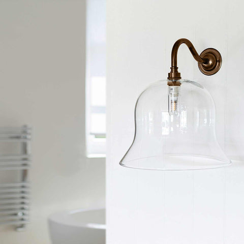 Large clear glass shade wall bathroom light with sleek design and water-resistant finish.