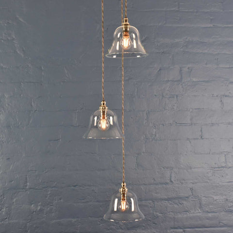 Bodium medium clear glass shade cluster pendant light with adjustable cords and hand-blown glass shades against a grey brick wall background