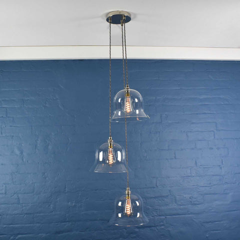 Bodium large clear glass shade cluster pendant light with adjustable cords and exposed filament bulbs against a blue brick wall background