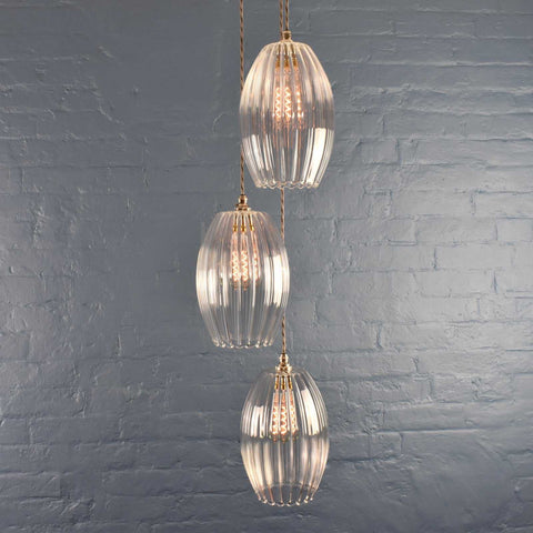 Camber Large Ribbed Glass cluster pendant light with three hanging oval ribbed glass shades against a grey brick wall background