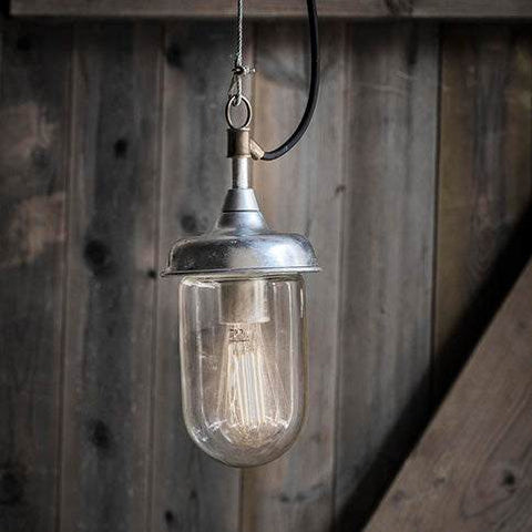 St Ives Harbour Outdoor Pendant Light in galvanized steel with vintage filament bulb and brass connector hanging against wooden background