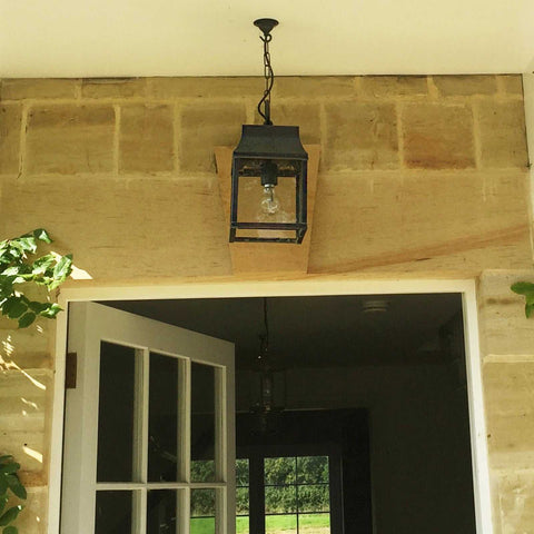 Kingsley Outdoor Hanging Lantern in black metal frame hanging on porch ceiling above entrance door