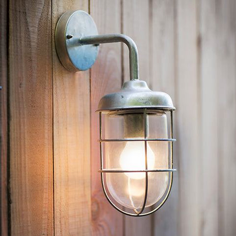 Stainless steel St Ives Harbour outdoor wall light with protective cage and glass shade mounted on wooden wall