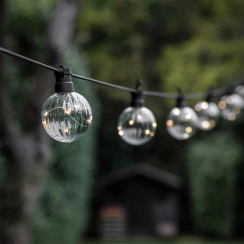 Festoon Linear Lights with 10 clear bulbs glowing warmly, strung outdoors in a garden setting