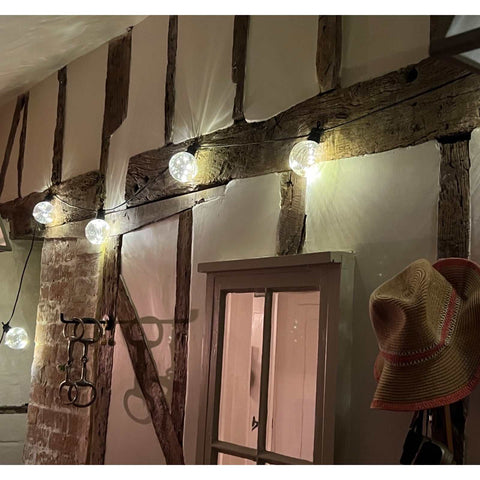 Festoon Linear Lights with 10 warm white bulbs hanging indoors on rustic wooden beams creating cozy ambient lighting.