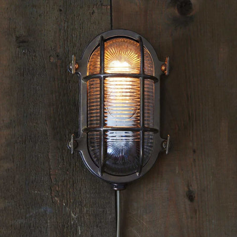 Ruben Small Outdoor Wall Light with nautical-inspired metal cage and glass cover mounted on rustic wooden wall