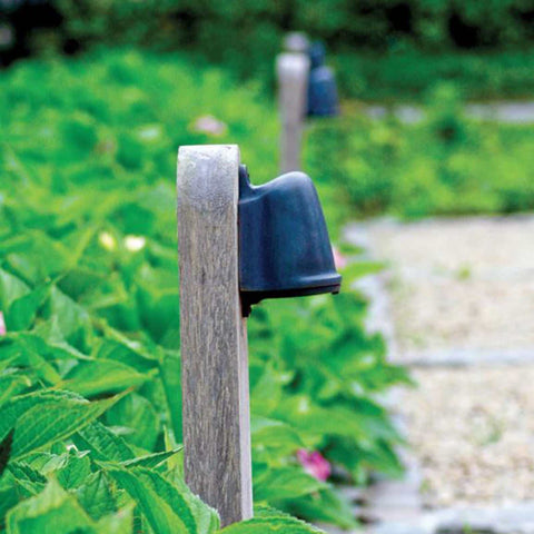 Bourne Outdoor Mast Light installed on wooden posts lining a garden pathway with greenery and gravel path visible