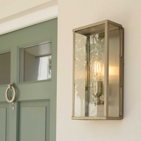 Large Chiswick Outdoor Wall Light with clear glass and metal frame mounted beside a green door