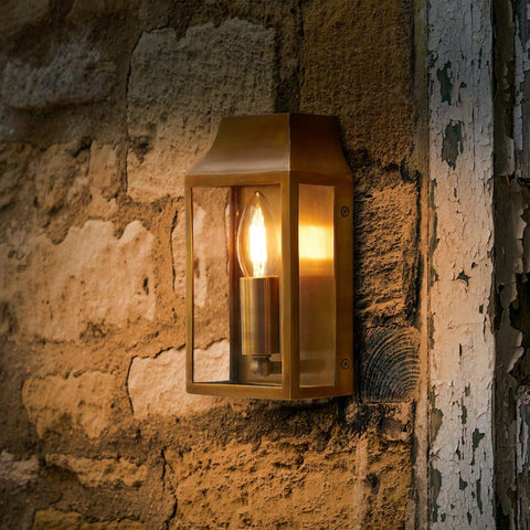 Pooky Crail Wall Light solid brass outdoor lantern-style fixture mounted on rustic stone wall with warm glow