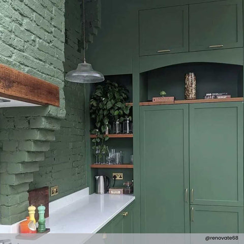 Mono prismatic pendant light with vintage prismatic glass shade hanging in green kitchen interior above white countertop.