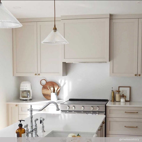 Rebell Prismatic Glass Pendant Light hanging in modern kitchen with beige cabinets and white countertop