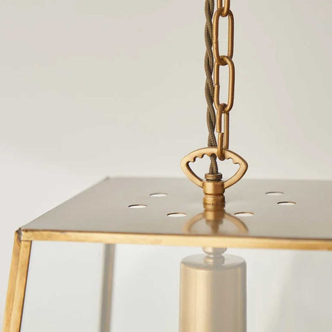 Close-up of large Luxor Lantern Pendant Light with clear glass panels and antique brass frame hanging from chain