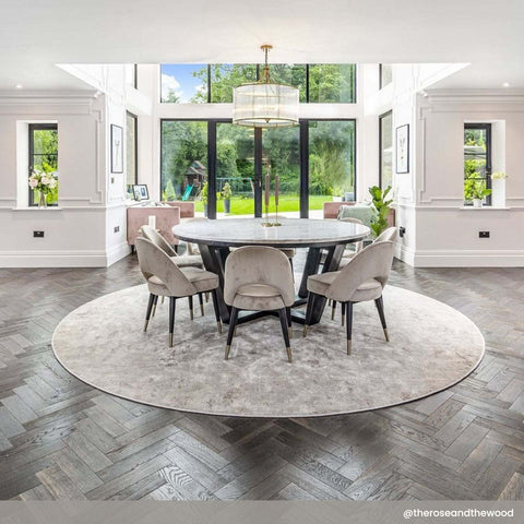 Artemis Chandelier pendant light with brass finish and glass rods hanging above round dining table in modern dining room