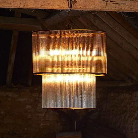 Loki Two-Tiered Oval Chandelier pendant light with brass frame and glass rods, emitting warm ambient light