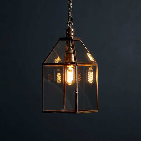 Medium Carrington Lantern Pendant Light with antique brass frame and glass shade illuminating with LED filament bulb