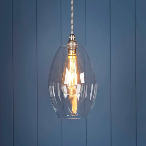 Camber medium clear glass shade pendant light with visible filament bulb against blue panel wall background