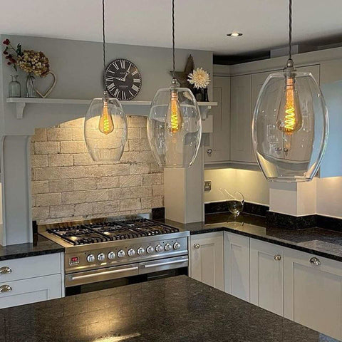 Camber large clear glass shade pendant lights with exposed filament bulbs hanging over a modern kitchen island