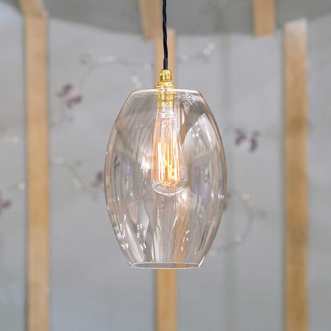 Camber large clear glass shade pendant light with exposed filament bulb hanging in modern interior