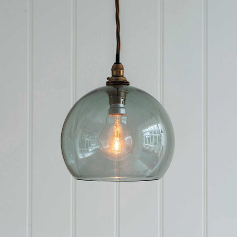 Soho Medium Smoked Glass Shade pendant light with a warm glowing bulb and twisted cord hanging against a white paneled wall