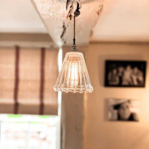 Rye small ribbed glass pendant light hanging from ceiling with warm glow in cozy room