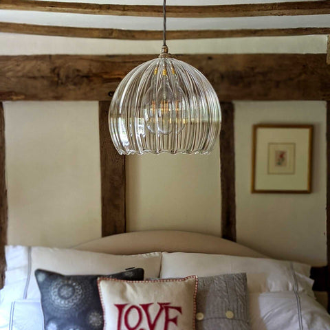Soho Extra Large ribbed hand blown glass globe pendant light hanging above a bed in a rustic bedroom