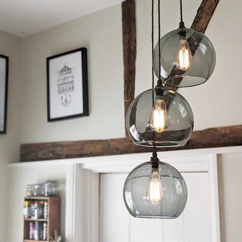 Soho large smoked glass shade cluster pendant light with three illuminated glass globes in a rustic interior