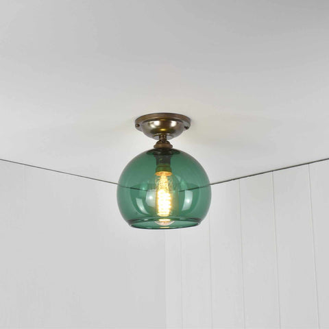 Soho small flush ceiling light with teal glass shade and vintage bulb in white room ceiling corner