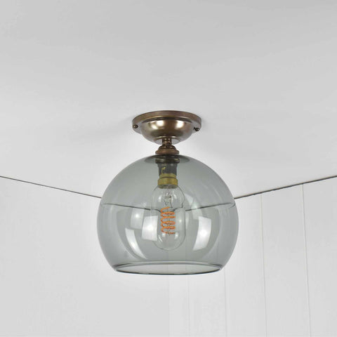 Soho Medium Smoked Glass Shade flush ceiling light with a smoked glass globe and antique brass finish, suitable for low ceilings.