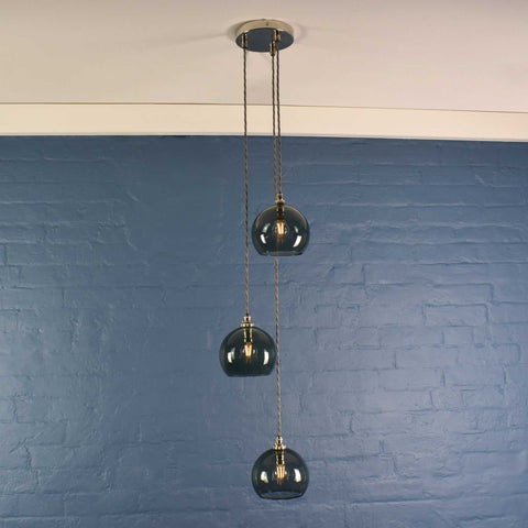 Soho small smoked glass shade cluster pendant light with adjustable cords against blue brick wall