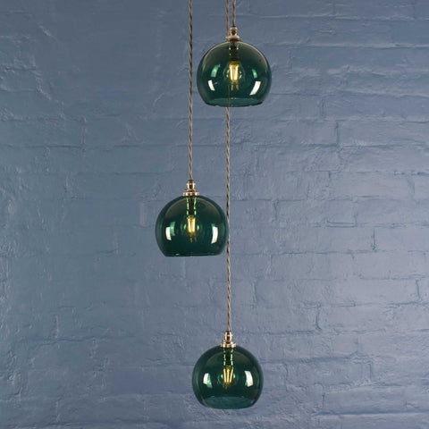 Soho small teal glass shade cluster pendant light with hand-blown globes and adjustable cords against blue brick wall
