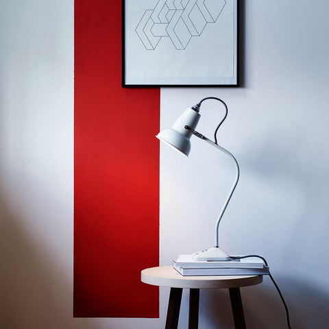 Anglepoise Original 1227 Mini Table Lamp in off white on a small table with books and modern wall art background