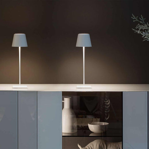 Zafferano Poldina Pro rechargeable white table lamps on modern cabinet against dark wall