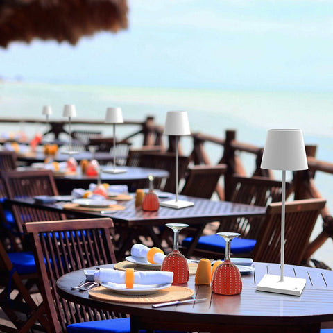 Zafferano Poldina Pro rechargeable white table lamp on outdoor dining tables by the sea