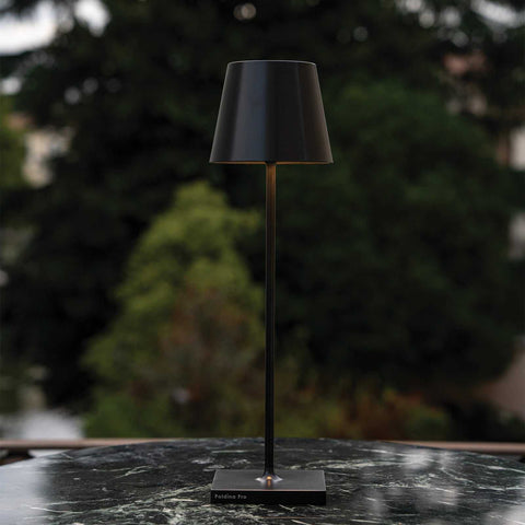 Zafferano Poldina Pro rechargeable black table lamp with sleek modern design on marble surface outdoors