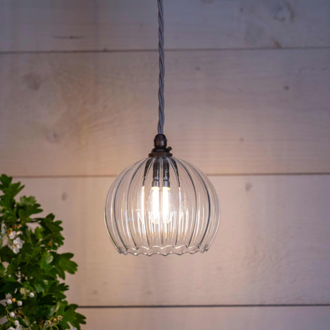 Soho small ribbed glass shade pendant light with hand-blown ribbed glass and warm glow hanging in a cozy room