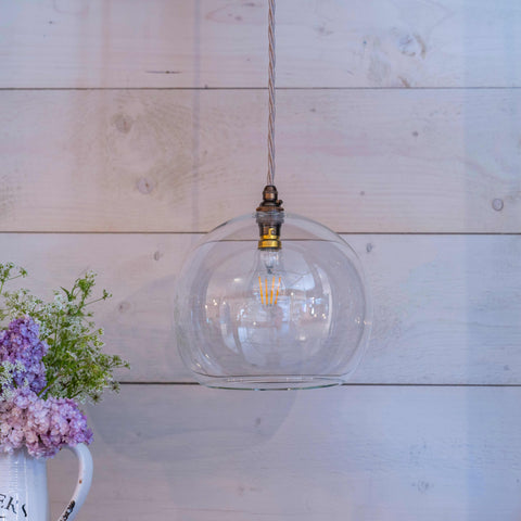 Soho large clear glass shade pendant light with bubble design hanging against wooden wall with flowers in vase nearby