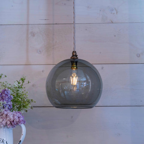 Soho large smoked glass shade pendant light with a bubble-like design hanging in a room with wooden wall background and flowers in a white vase nearby