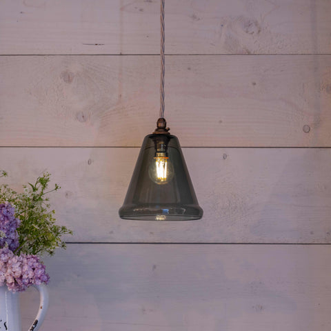 Rye Small Smoked Glass pendant light with hand-blown smoked glass shade hanging against a wooden wall